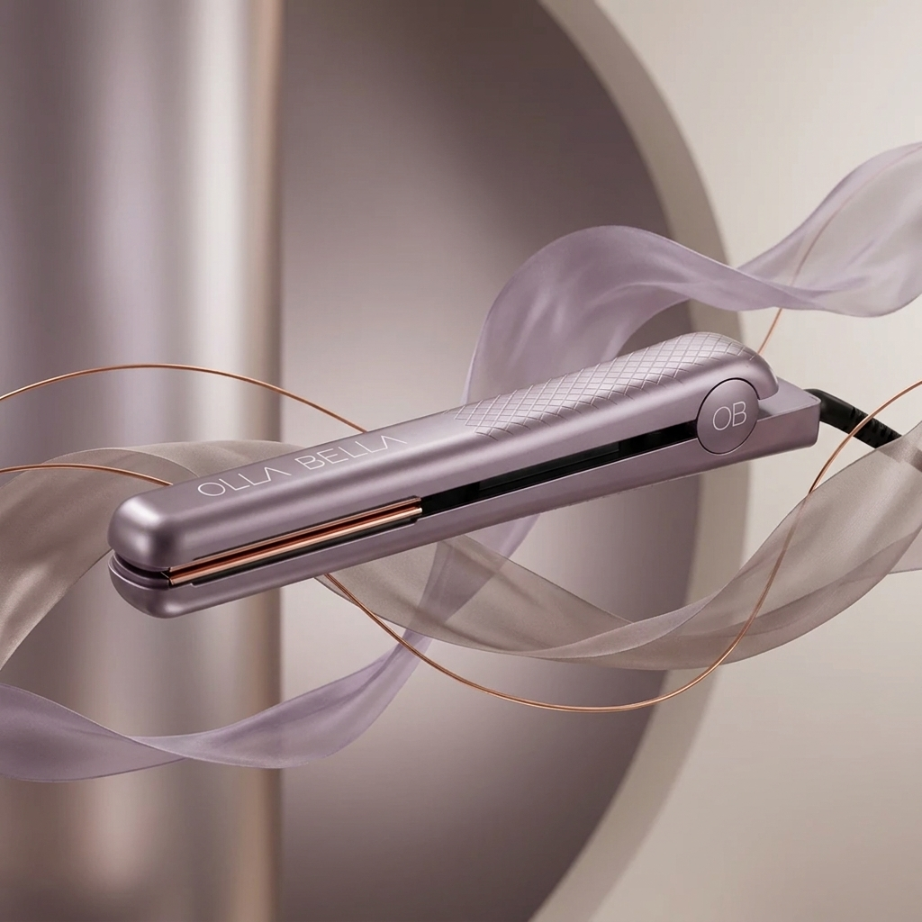 A close-up of a Plum Metallic Olla Bella 1.25" Ceramic Hair Straightener floating amidst flowing sheer lavender ribbons.