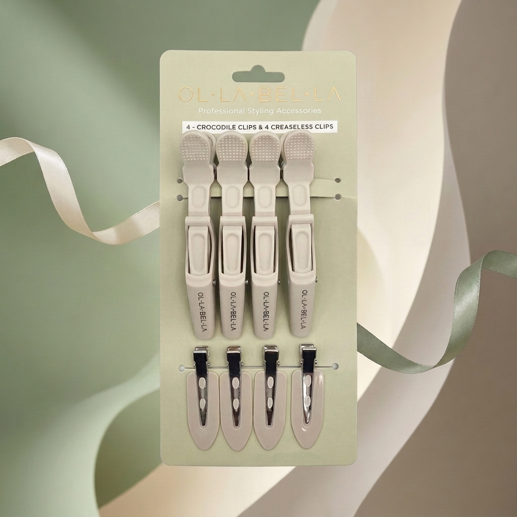 The Olla Bella Mane Master Hair Clip Set which includes four crocodile clips and four creaseless clips, presented on a light sage green backing card. The clips are a warm cream color.