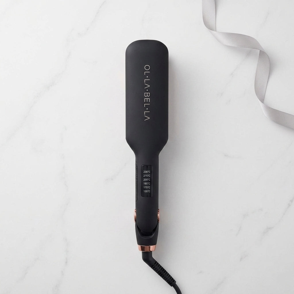 An Olla Bella 2" Wide Plate Flat Iron Hair Straightener with rose gold accents, shown from a top-down view on a white marble background with a white ribbon.